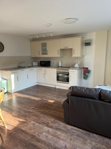 a living room with a couch and a kitchen at Hanley Swan, The Garden Flat in Madresfield
