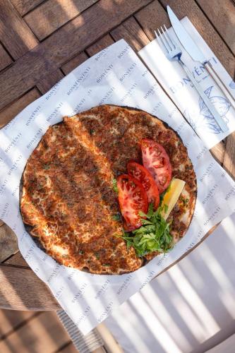 a pizza sitting on a table with tomatoes on it at Voger Bodrum by The Sea in Yalıkavak