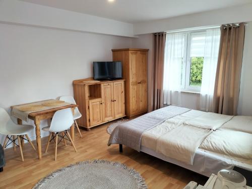 a bedroom with a bed and a table and a television at Pokoje u Bożeny in Ostrowo