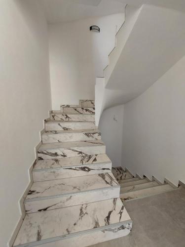 a white staircase with marble floors and white walls at Top Apartments in Dobra Voda