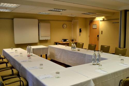 a meeting room with tables and chairs with white table cloth at Holiday Inn Northampton by IHG in Northampton