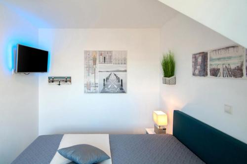 Un dormitorio con una cama y un televisor y fotos. en Erholung am Deich- Ihre Ferienwohnung in Tossens, en Tossens