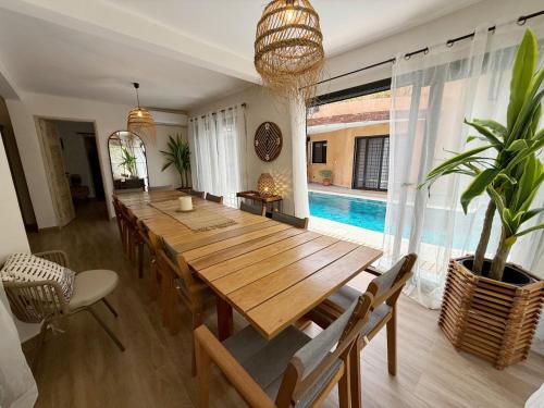 a dining room with a wooden table and a pool at Agence Adjana Resort - Résidence du Port 3 in Sali Tapé