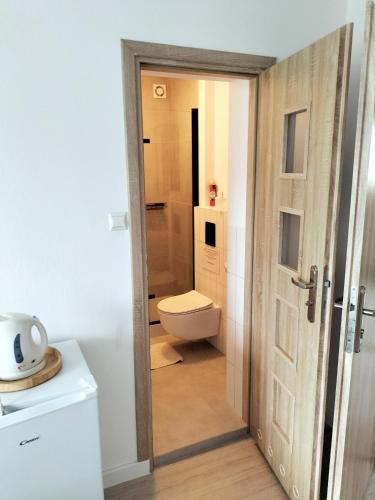 a bathroom with a white toilet and a door at Pokoje u Bożeny in Ostrowo