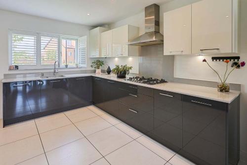 a large kitchen with white cabinets and black appliances at Host & Stay - Maison de Cobbe in Winchester
