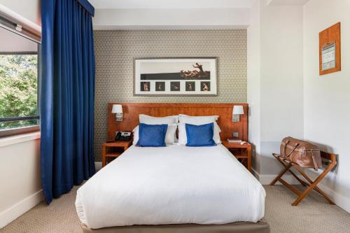 a bedroom with a bed with blue curtains and a window at Crowne Plaza Lyon - Cité Internationale in Lyon