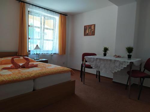 a bedroom with a bed and a table and a window at Penzion SIESTA in Příbor