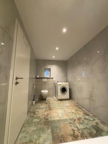 a bathroom with a toilet and a washing machine at Modernes Apartment mit Parkplatz in Elsdorf
