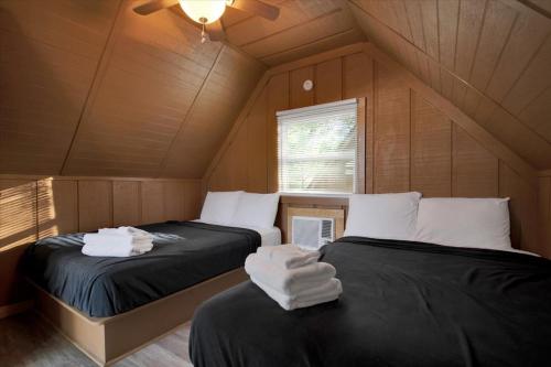 deux lits dans une chambre aux murs et plafonds en bois dans l'établissement Cozy Cabin Near Dollywood with Parking, à Pigeon Forge