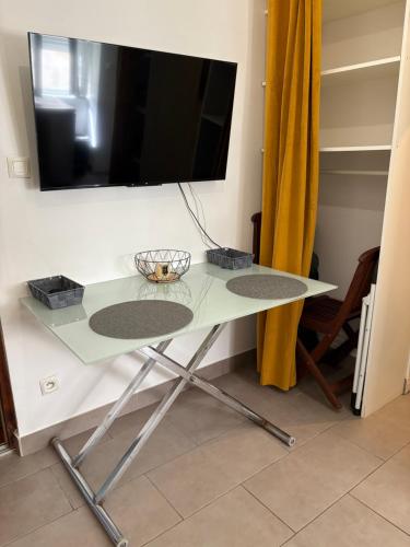 une table en verre avec une télévision sur un mur dans l'établissement Charmant studio en centre-ville, à Ajaccio