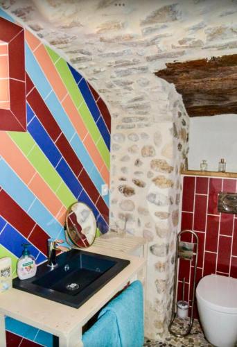 une salle de bain avec un lavabo et un mur en pierre dans l'établissement Le Mas Charamèlia, à Saint-Victor-de-Malcap