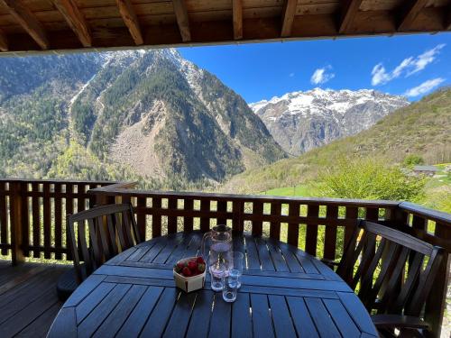 a table with wine glasses and a box of fruit on a deck at Les Cristallieres Venosc in Vénosc