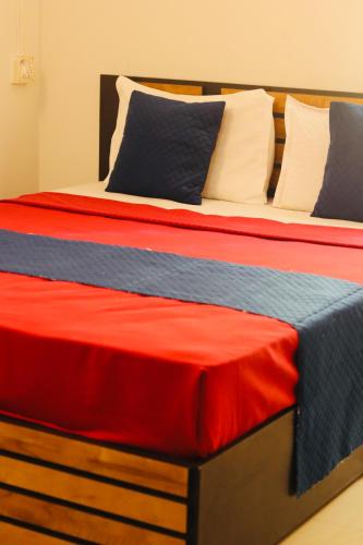 a bed with red and blue sheets and pillows at AquaTerra Comfy stay Varkala beach in Varkala