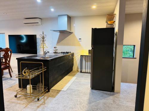 a kitchen with a sink and a black refrigerator at 天空の麓糸島 屋上パノラマ奇跡の眺望 露天風呂絶景サウナ bbq 16名以上 駐車場6台 ペット in Itoshima