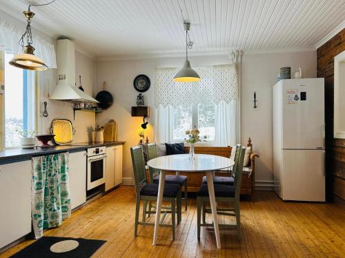 a kitchen with a table and a white refrigerator at Fyra rum och kök i Mellanfjärden in Mellanfjärden