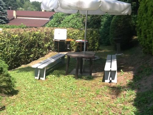 a picnic table and a bench with an umbrella at Apartmán na loučkách u lesa in Dolany