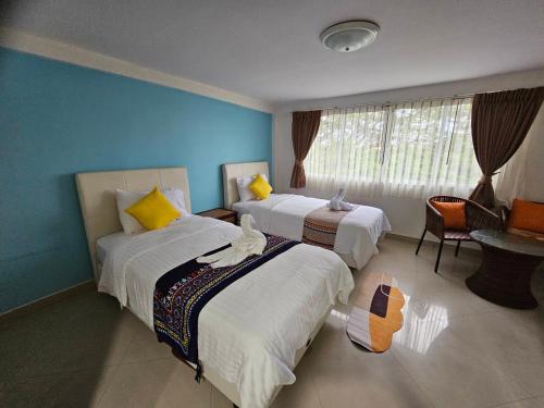 a hotel room with two beds and a window at Hello Jomtien in Jomtien Beach