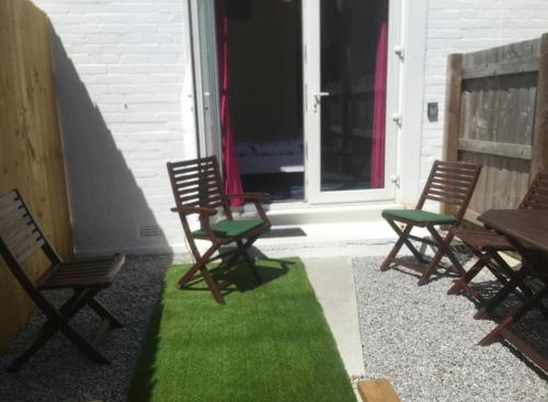a group of chairs sitting on a porch with green grass at Paignton seafront Apartment with Private Garden ,FREE Private Car Space FREE WIFI ,No kitchen but Fridge Tea coffee Towels YES Double & Single bed YES Reception to help you YES Opposite the Beach Yes in Paignton