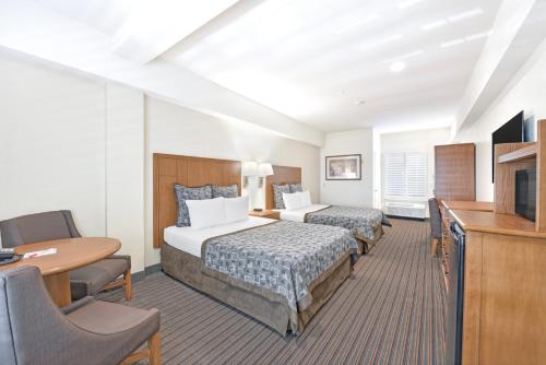 a hotel room with two beds and a desk at Anaheim Desert Inn & Suites in Anaheim