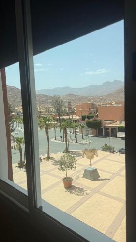 a window with a view of a courtyard with trees at Fibule d'or in Tafraoute