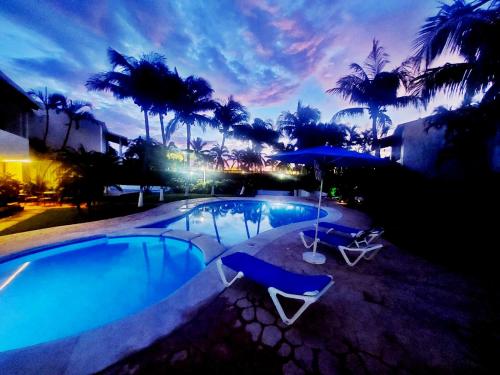 a swimming pool with two chairs and an umbrella at Hermosa planta baja con piscina, acceso a la Playa!!! in Cancún