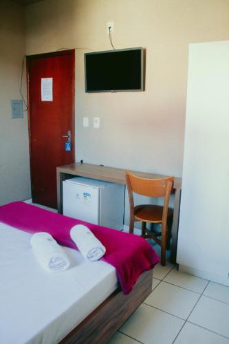 a bedroom with a bed and a desk with a tv at Hotel Maia in Betim