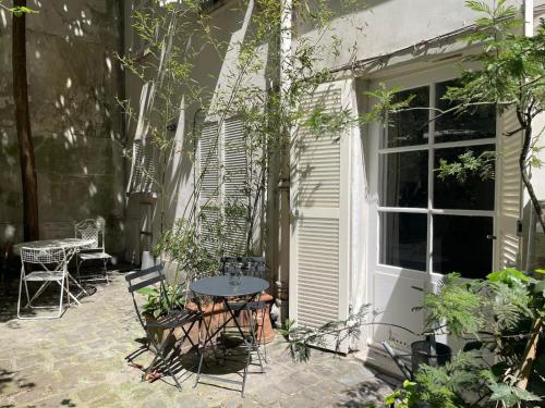 un patio avec une table et des chaises à côté d'un bâtiment dans l'établissement Chic neighborhood charming courtyard studio 7th, à Paris