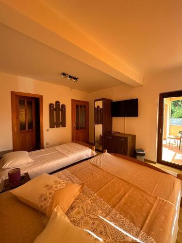 two beds in a large room with a window at Vila Camelia in Eforie Nord