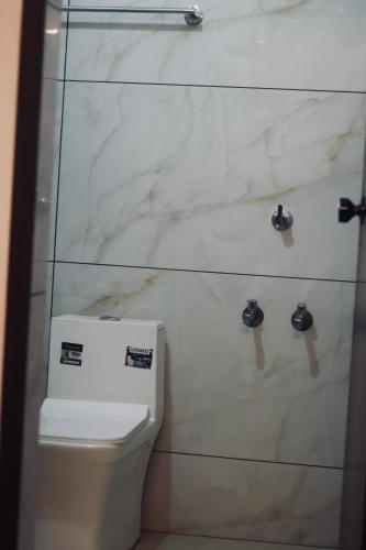 a bathroom with a toilet and a marble wall at AquaTerra Comfy stay Varkala beach in Varkala