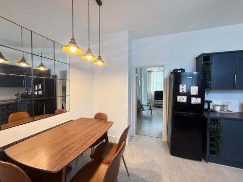 a kitchen with a wooden table and a black refrigerator at Bee Stays - Pickmere House in Warrington