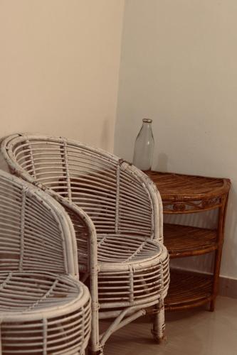 a wicker chair next to a table and a vase at AquaTerra Comfy stay Varkala beach in Varkala