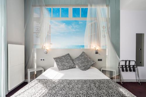 a bedroom with a bed and a large window at Hotel des Ducs in Alençon