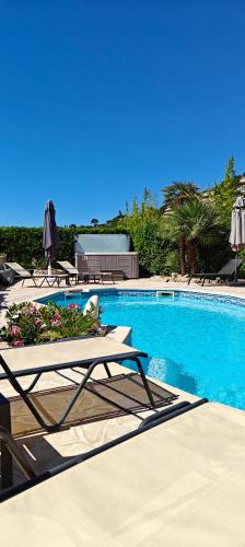 une piscine avec deux tables de salon et des parasols dans l'établissement VILLA PLEIN SUD-Piscine-Spa-Climatisation-Parking privé-calme et détente, à Cavalaire-sur-Mer