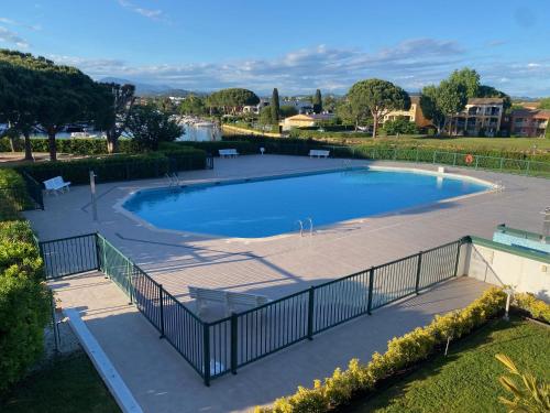 une grande piscine entourée d'une clôture. dans l'établissement Beau Studio dans résidence de standing avec 2 piscines proche des commerces, transport et plage, à Mandelieu-la-Napoule