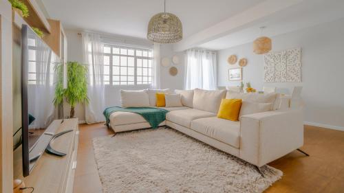 a living room with a white couch and a tv at Family House in Campanário
