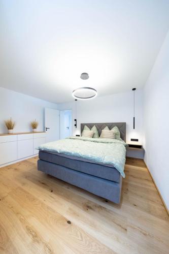 Un dormitorio con una cama grande con paredes blancas y suelos de madera. en Blütenzauber am Mondsee, en Mondsee