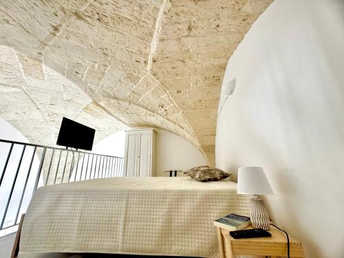 a bedroom with a bed with a stone wall at Pozzelle Holiday House in Zollino