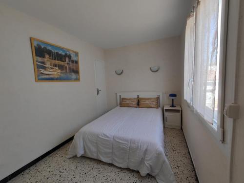 une chambre blanche avec un lit et une fenêtre dans l'établissement Maison Côté Plage Grau d'agde, au Grau-dʼAgde