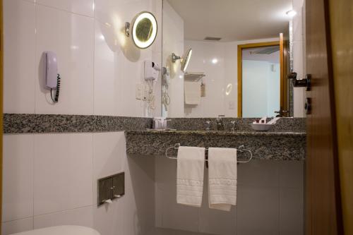 a bathroom with a sink and a toilet and a mirror at Scorial Rio Hotel in Rio de Janeiro