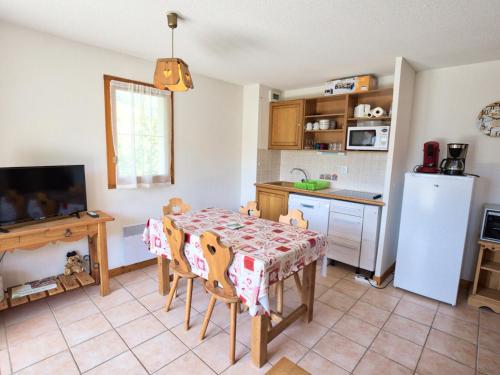une cuisine avec une table avec des chaises et un réfrigérateur dans l'établissement Appartement au pied des pistes avec grande terrasse et parking - FR-1-505-36, à Flumet