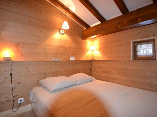 Un dormitorio con una cama en una pared de madera. en Charmant appart 4/5 pers au pied des pistes avec balcon, Wifi, parking, animaux OK - FR-1-505-65, en Notre-Dame-de-Bellecombe