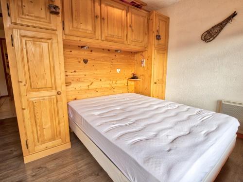un lit dans une chambre avec un mur en bois dans l'établissement Charmant appartement familial avec parking et animaux acceptés - FR-1-505-63, à Notre-Dame-de-Bellecombe