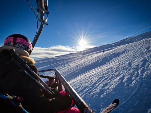 une personne à bord d'une remontée mécanique sur une piste enneigée dans l'établissement Charmant appart 4/5 pers au pied des pistes avec balcon, Wifi, parking, animaux OK - FR-1-505-65, à Notre-Dame-de-Bellecombe