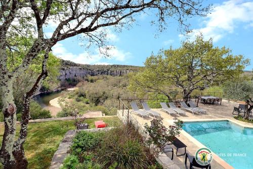 - une piscine avec des chaises et une vue sur la rivière dans l'établissement Villas Nature et liens, à Saint Alban Auriolles