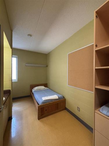 a small room with a bed and shelves in it at Hotel Laurier - King Street Residence in Waterloo