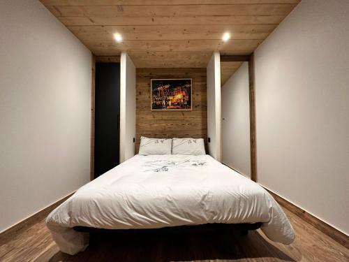 une chambre avec un lit avec un tableau sur le mur dans l'établissement Appartement moderne au cœur de Notre-Dame-de-Bellecombe, proche pistes et commodités - FR-1-505-185, à Notre-Dame-de-Bellecombe
