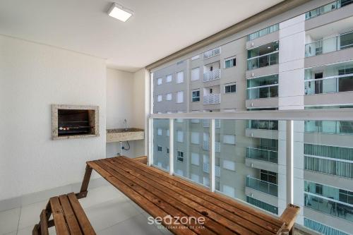 a balcony with a wooden bench in front of a building at Condomínio a beira-mar c/ piscina - SHC in Piçarras