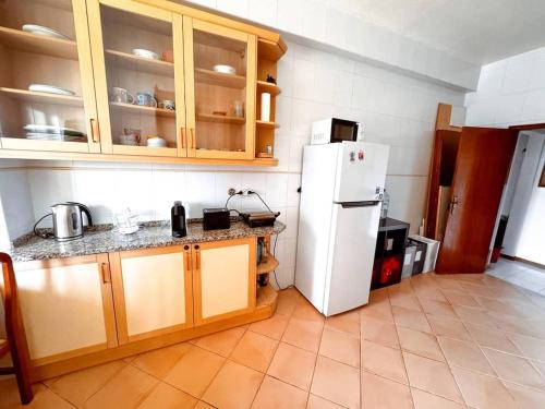 a kitchen with a white refrigerator and wooden cabinets at Big Sunset Private Room in Oeiras