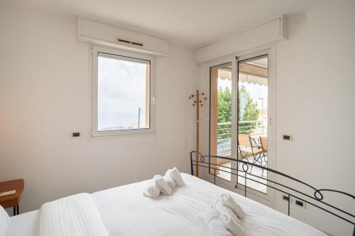 une chambre blanche avec un lit et un balcon dans l'établissement Montecarlo vista - Sea view, à Beausoleil