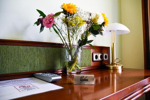 a vase of flowers sitting on a desk at Parkhotel Zirndorf in Zirndorf